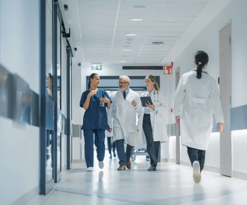 health-centers-header A group of doctors walking down a hallway, having a discussion.