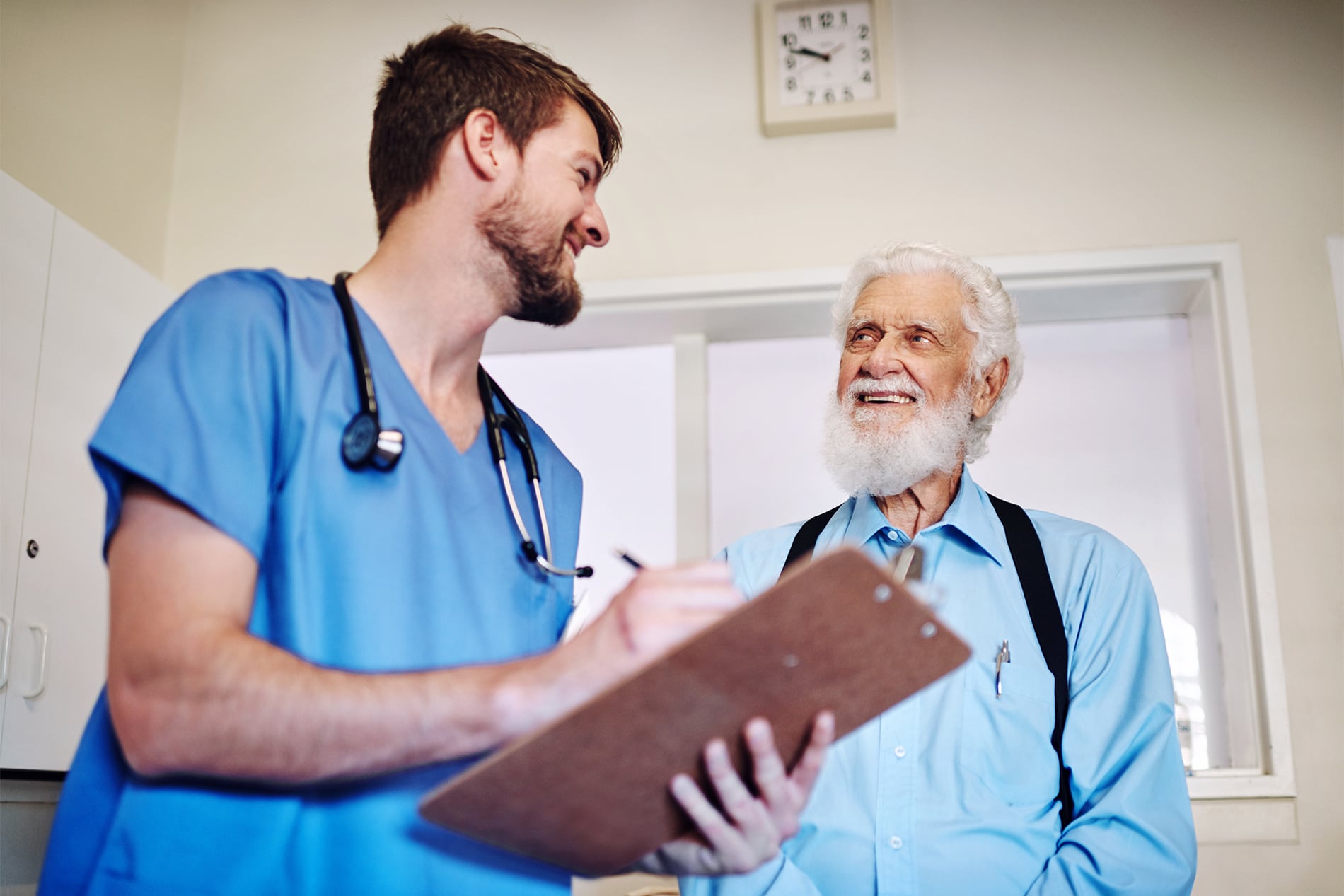 why-work-at-wyoming-health-center-cta A male nurse talking to an elderly man about his chart.